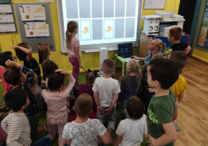 Dzieci stoją przed tablicą interaktywną.