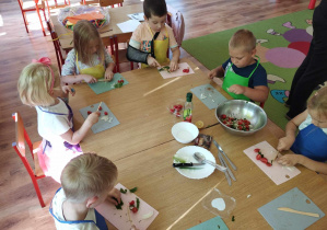 Dzieci kroją składniki na sałatkę.