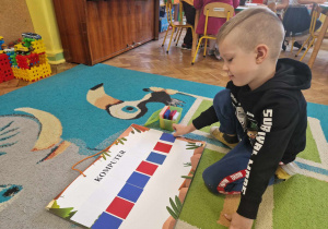 Chłopiec dzieli wyraz na samogłoski i spółgłoski układa kartoniki pod wyrazem