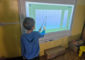 Chłopiec przelicza elementy na tablicy interaktywnej