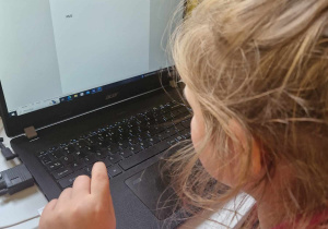 Dziewczynka pisze na komputerze swoje imię