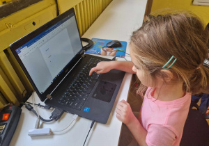 Dziewczynka pisze na komputerze swoje imię