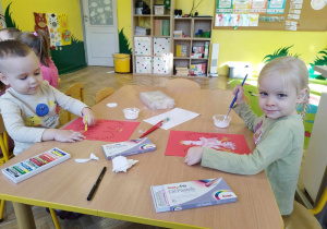Chłopiec i dziewczynka wykonują pracę plastyczną "Godło Polski"
