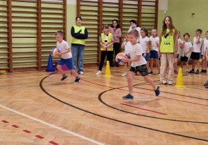 Chłopiec biegnie z piłką po wyznaczonym torze