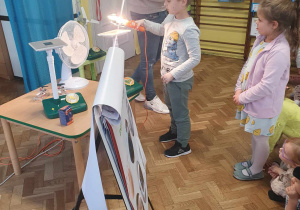 Chłopiec oświetla lampą panel fotowoltaiczny.