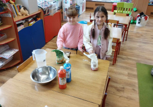 Dwie dziewczynki wsypują mąkę do szklanek.