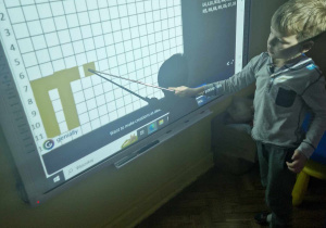 Chłopiec koduje obrazek andrzejkowy na tablicy interaktywnej