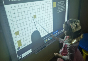 Dziewczynka koduje obrazek andrzejkowy na tablicy interaktywnej