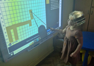 Dziewczynka koduje obrazek andrzejkowy na tablicy interaktywnej