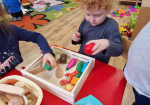 Dzieci bawią się drewnianymi warzywami w kąciku kuchennym