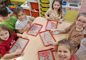 Dzieci rysują palcem na tacce z piaskiem