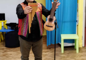 Mężczyzna z Peru pokazuje tradycyjne instrumenty muzyczne: fletnię i charango.