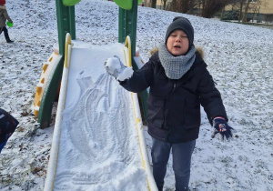 Chłopiec trzyma w ręce kulkę śniegu