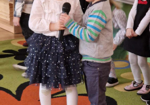 Dwoje dzieci recytuje wiersz przez mikrofon