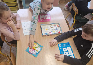 Dzieci grają w grę stolikową dotyczącą znajomości kolorów