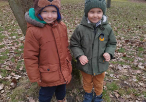 Chłopcy stoją przy drzewie.