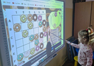 Dziewczynka układa pączki w/g kodu na tablicy interaktywnej