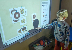 Chłopiec dobiera pączki do pary w grze na tablicy interaktywnej