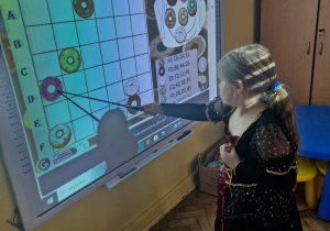 Dziewczynka układa pączki w/g kodu na tablicy interaktywnej