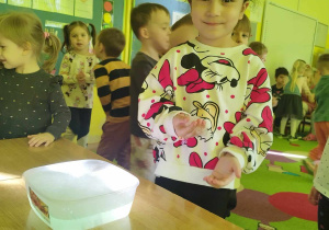 Dziewczynka uczestniczy w eksperymencie z suchym lodem, wodą i płynem do naczyń.