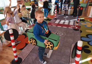 Chłopiec w modelu samochodu porusza się po makiecie drogi