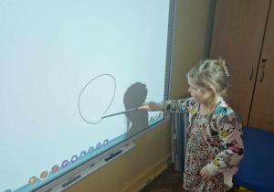 Dziewczynka rysuje na tablicy interaktywnej sylwete kota