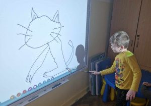 Chłopiec rysuje na tablicy interaktywnej kota