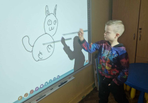 Chłopiec rysuje na tablicy interaktywnej sylwete kota
