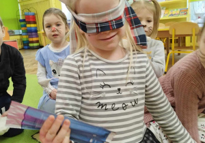 Dziewczynka z zakrytymi oczami zgaduje jaki przedmiot trzyma w dłoniach