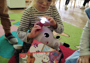 Dziewczynka w stroju kota rozwiązuje zagadkę podświetlaną latarką