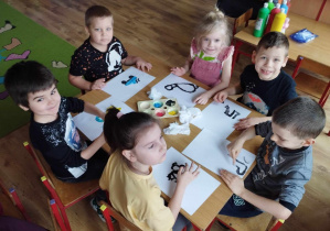 Dzieci siedzą przy stole i malują palcami ulubione zabawki