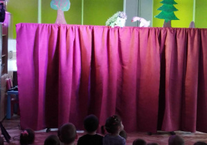 Dzieci oglądają przedstawienie teatralne przed kukiełki jeża i gąski