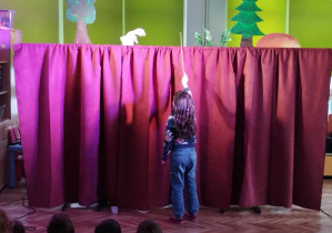 Na scenie widać dziewczynkę, która zagania patyczkiem gąskę