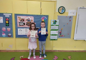 Dziewczynka i chłopiec prezentują swoje dyplomy