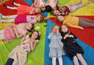 Dziewczynki leżą na kolorowej chuście animacyjnej