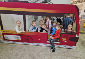 Dzieci siedzą w makiecie tramwaju