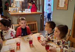Dzieci jedzą ciasteczka i piją sok w baśniowej kawiarence.