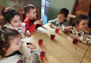 Dzieci jedzą ciasteczka i piją sok w baśniowej kawiarence.