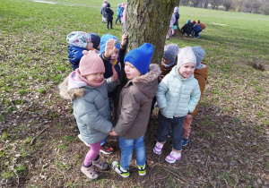 Dzieci stoją wkoło drzewa
